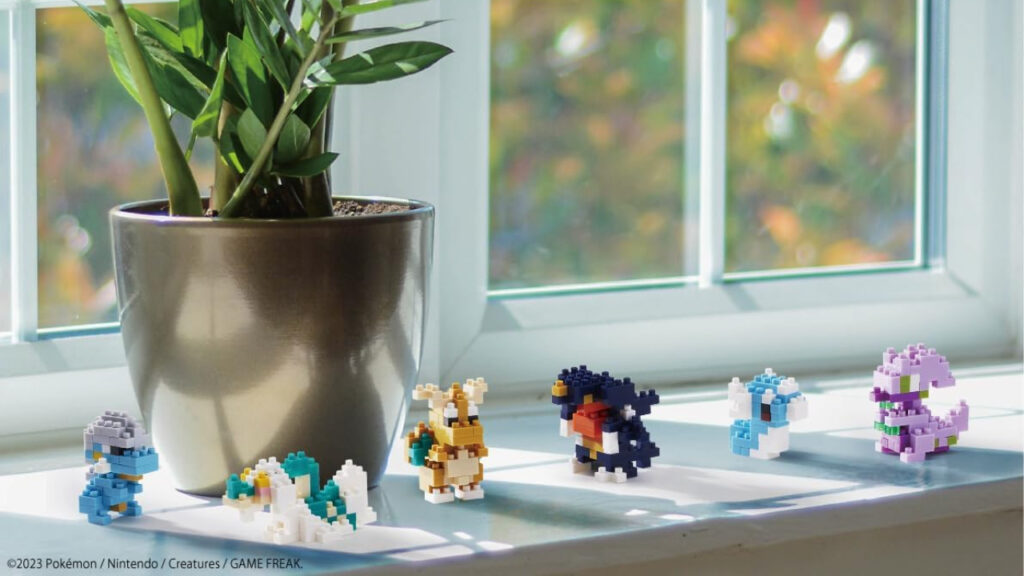 A set of Nanoblocks Pokemon are sitting on a window-sill. They're next to a plant pot.