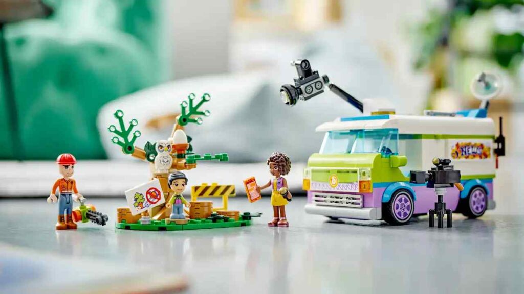 A shot of the LEGO Newsroom Van. There's minifigures in the foreground, and a tree surgeon whose being stopped from chopping down a tree by a protestor.