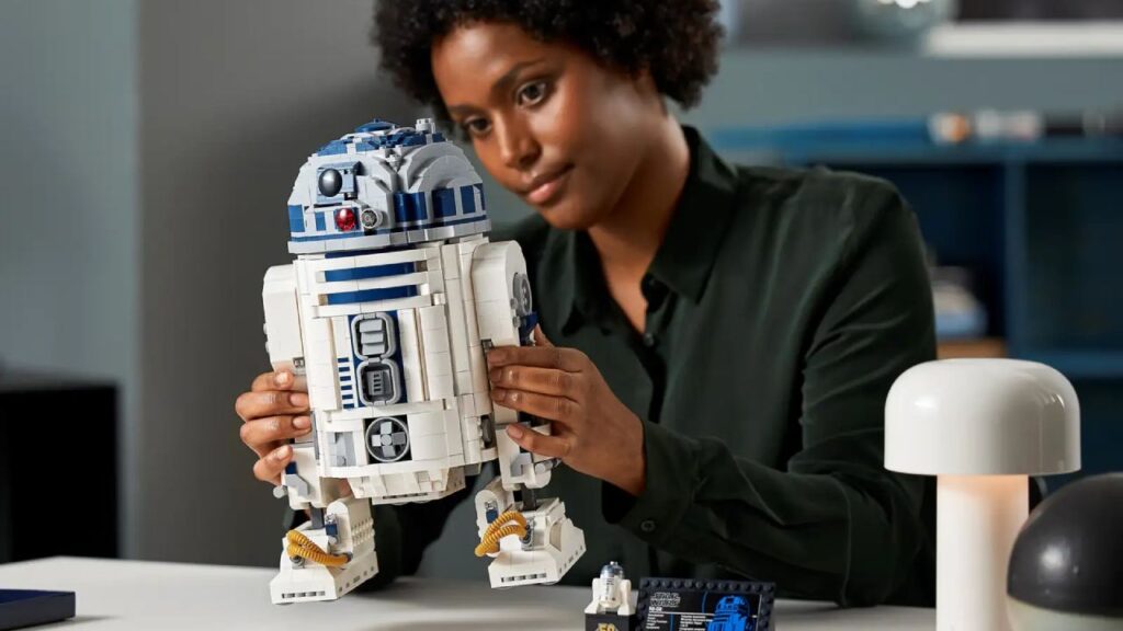 The 75308 LEGO R2D2 held in the hands of a LEGO builder.