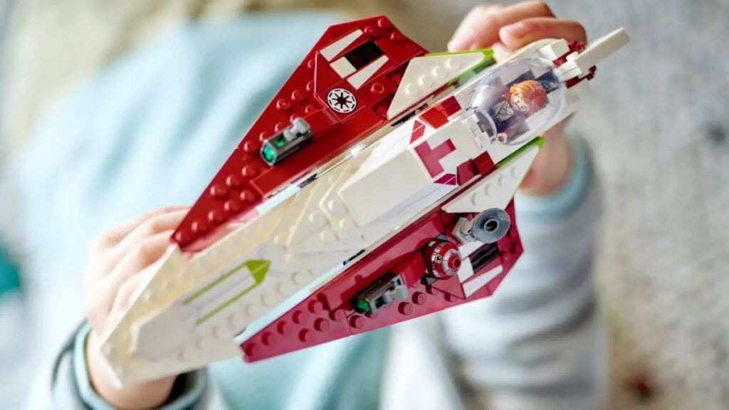 A pair of hands are holding the Obi Wan Kenobi's Jedi Starfighter model.
